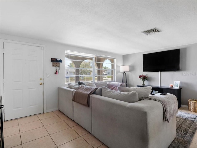 living area featuring a textured ceiling, light tile patterned flooring, and visible vents