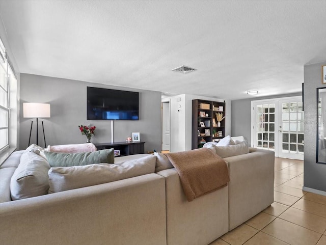 living area featuring french doors, visible vents, a textured ceiling, and light tile patterned floors