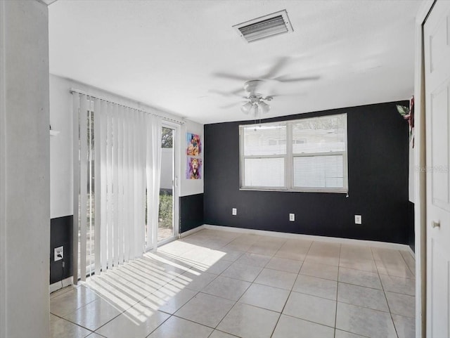 empty room with baseboards, light tile patterned flooring, visible vents, and a ceiling fan