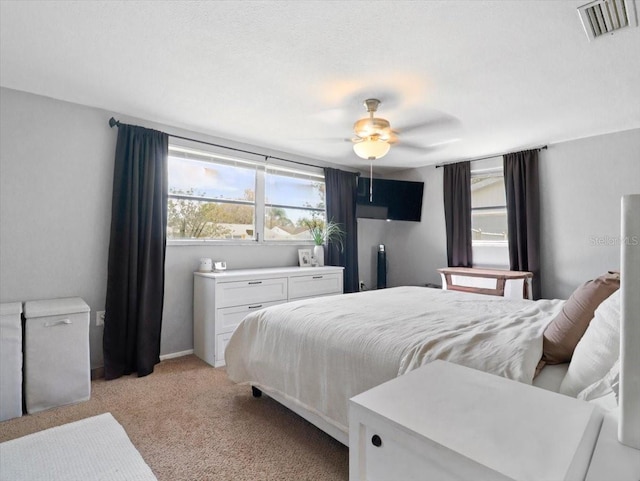 bedroom with light carpet, ceiling fan, and visible vents