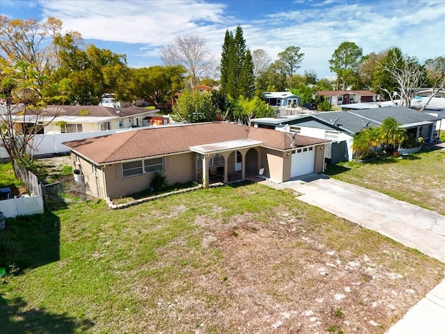 single story home with driveway, a residential view, an attached garage, fence, and a front lawn