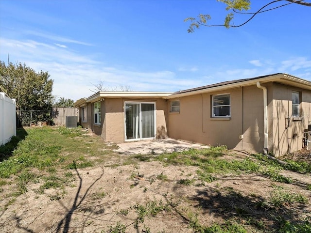 back of house featuring central AC unit, fence, and stucco siding