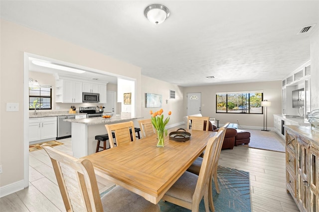 dining area featuring light wood-style floors, baseboards, and visible vents