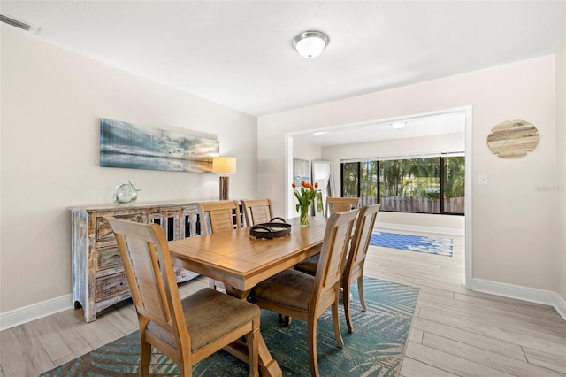 dining area featuring visible vents, baseboards, and light wood finished floors