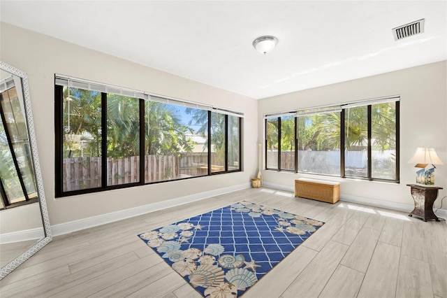 living area with plenty of natural light, wood finished floors, visible vents, and baseboards