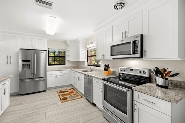 kitchen featuring visible vents, white cabinets, stainless steel appliances, and a sink