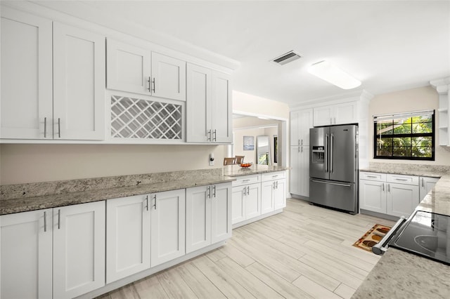 kitchen with visible vents, white cabinetry, light wood-style floors, stainless steel fridge with ice dispenser, and light stone countertops