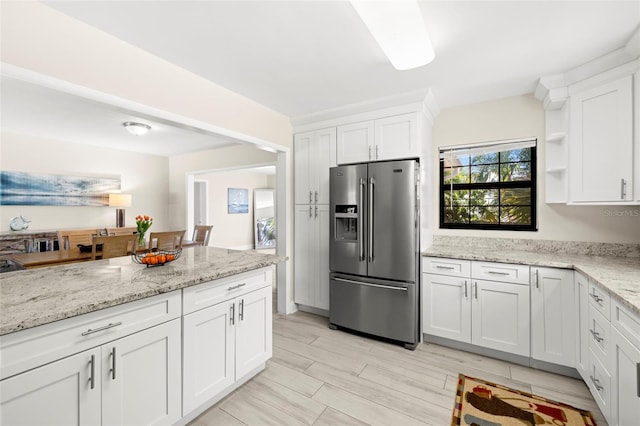 kitchen with wood finish floors, open shelves, white cabinetry, stainless steel fridge with ice dispenser, and light stone countertops