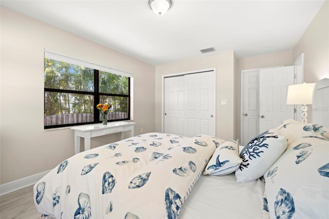 bedroom featuring wood finished floors, baseboards, a closet, and visible vents