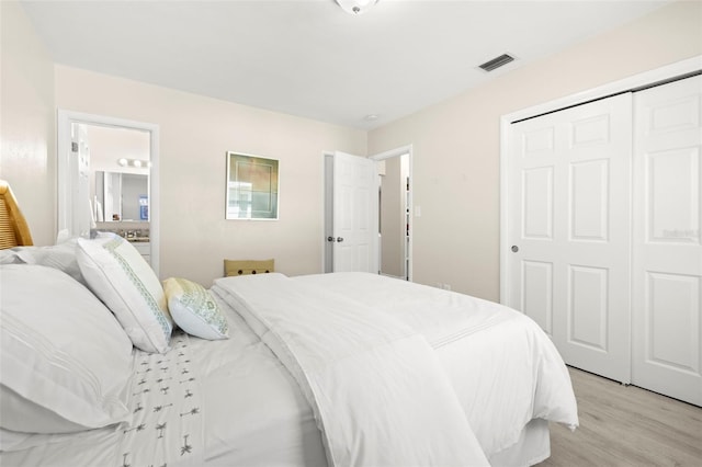 bedroom featuring visible vents, light wood-style floors, a closet, and connected bathroom