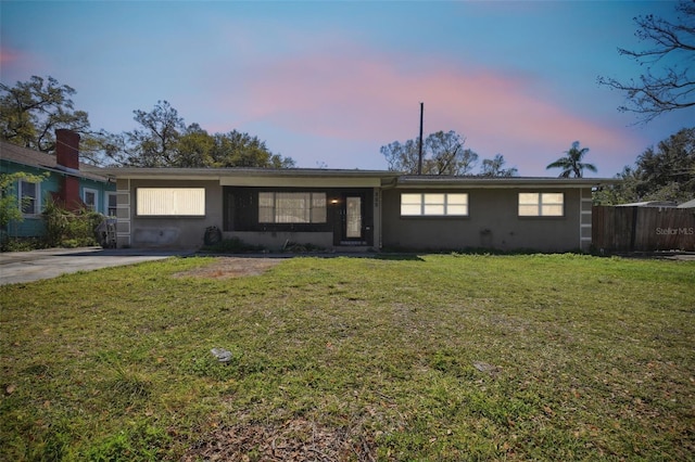 view of front of house featuring stucco siding, a yard, and fence