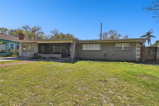 single story home with stucco siding, a front yard, and fence