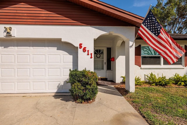 view of front facade with a garage, driveway, a front yard, and stucco siding