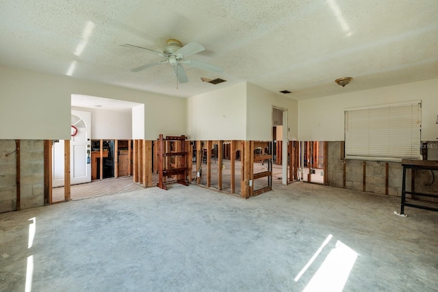 unfurnished room with a textured ceiling, ceiling fan, concrete floors, and visible vents