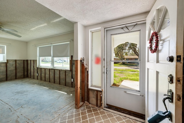 entryway featuring a wainscoted wall, a textured ceiling, and a ceiling fan