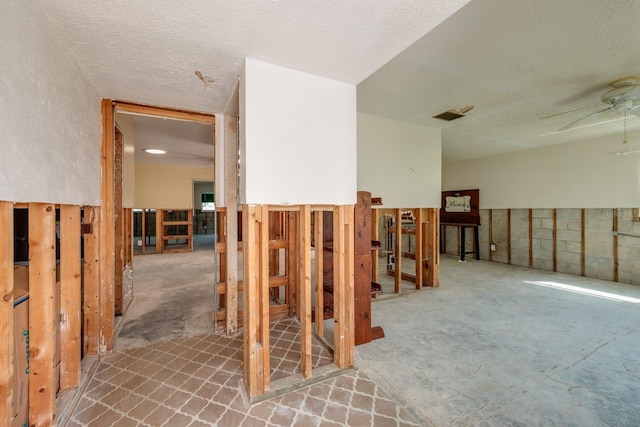 interior space featuring concrete block wall, visible vents, and a textured ceiling