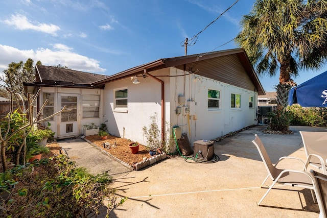 rear view of house featuring a patio area, fence, and stucco siding