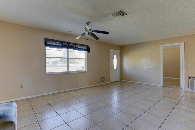 unfurnished room featuring light tile patterned floors, a textured ceiling, visible vents, baseboards, and a ceiling fan