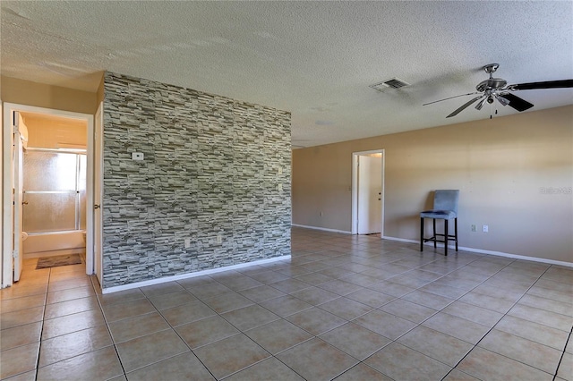 unfurnished room featuring ceiling fan, a textured ceiling, visible vents, baseboards, and tile patterned floors