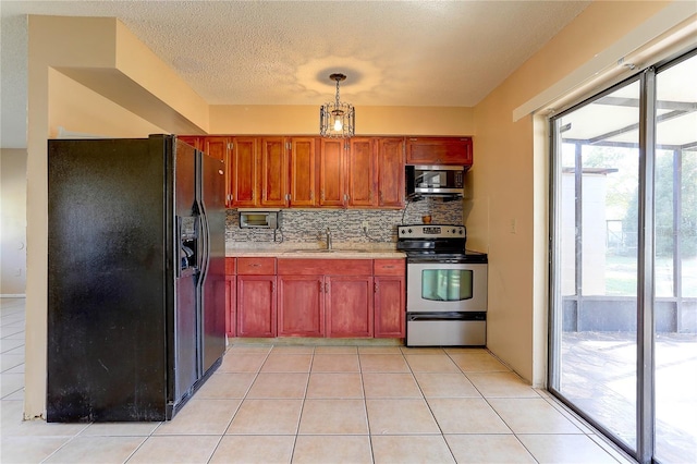 kitchen featuring decorative light fixtures, light countertops, appliances with stainless steel finishes, light tile patterned flooring, and a sink