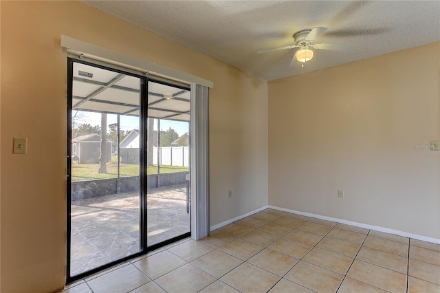 empty room with light tile patterned floors, ceiling fan, a textured ceiling, and baseboards