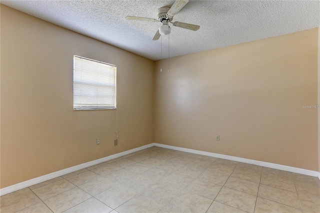 empty room with a textured ceiling, light tile patterned floors, a ceiling fan, and baseboards