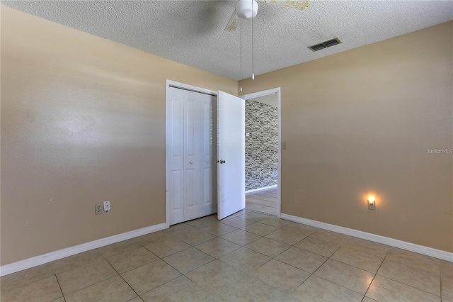 unfurnished room featuring visible vents, light tile patterned flooring, ceiling fan, a textured ceiling, and baseboards