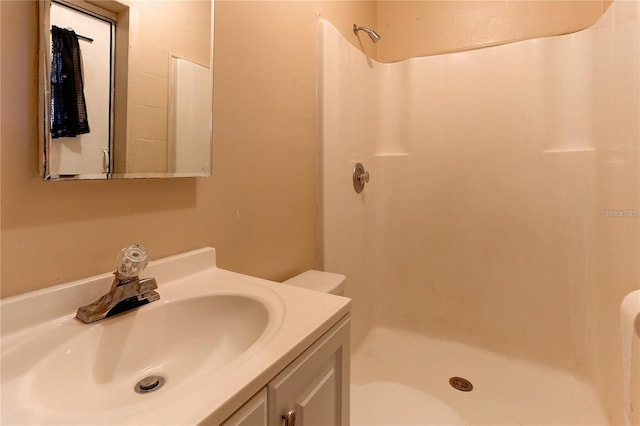 full bathroom with walk in shower, vanity, and toilet