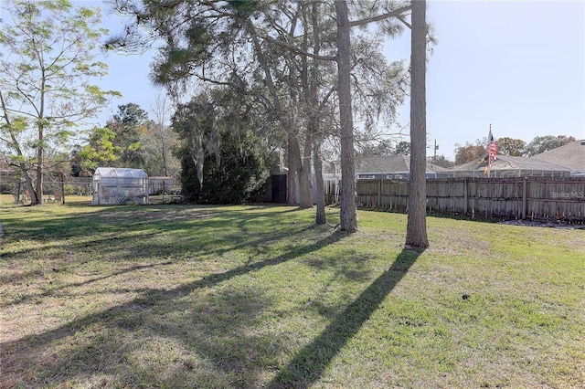 view of yard featuring an outbuilding, a greenhouse, and a fenced backyard