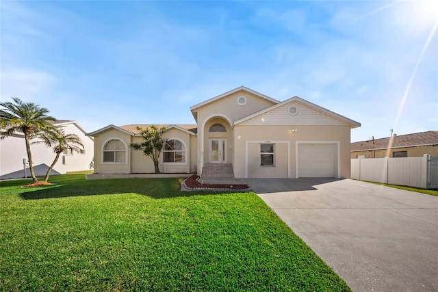 view of front facade with fence, a front yard, stucco siding, a garage, and driveway