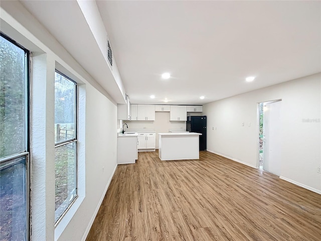 kitchen with light countertops, light wood-style floors, freestanding refrigerator, open floor plan, and white cabinetry