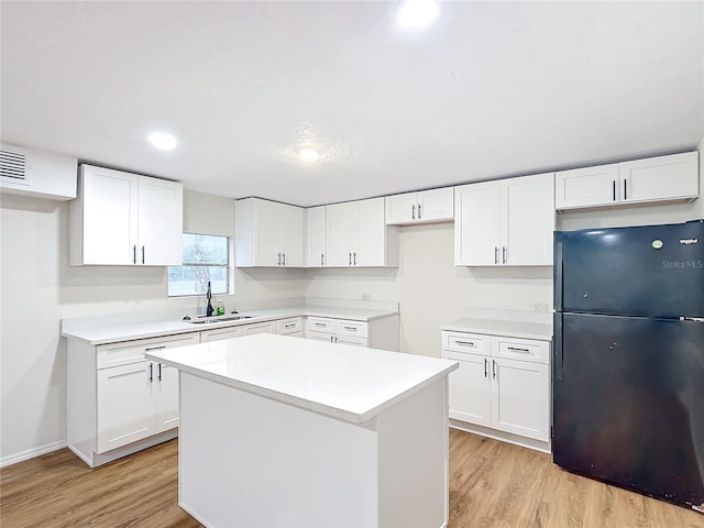 kitchen featuring light countertops, freestanding refrigerator, and white cabinetry