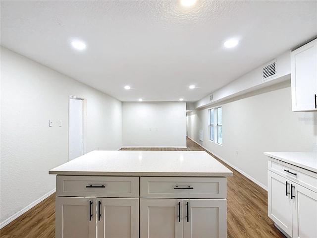 kitchen featuring visible vents, white cabinets, a kitchen island, wood finished floors, and recessed lighting