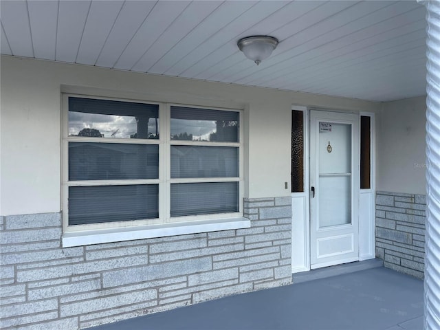 view of exterior entry with stone siding and stucco siding