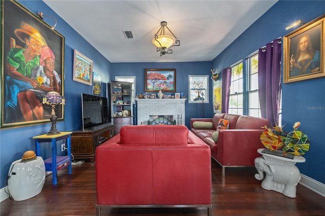 living area with a brick fireplace, baseboards, and dark wood-style floors