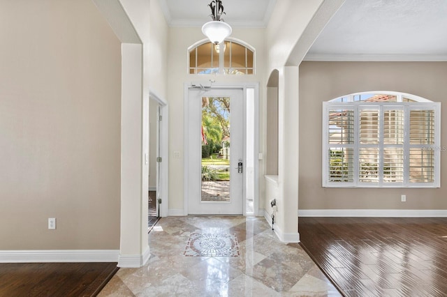 foyer entrance with arched walkways, ornamental molding, and baseboards