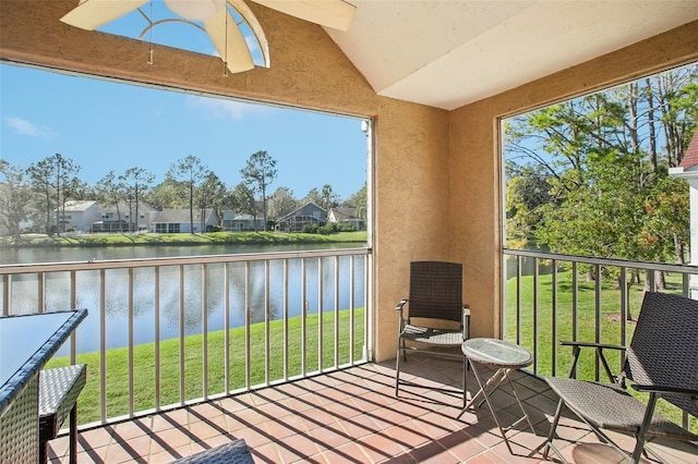 sunroom with lofted ceiling, a water view, and a residential view