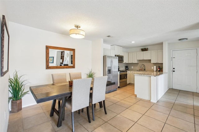 dining room with light tile patterned floors, a textured ceiling, and recessed lighting