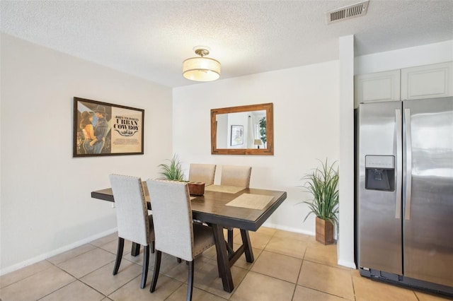 dining area with visible vents, a textured ceiling, and light tile patterned flooring