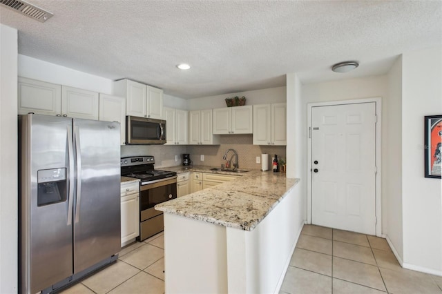 kitchen featuring appliances with stainless steel finishes, white cabinets, visible vents, and a sink