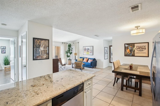 kitchen featuring visible vents, appliances with stainless steel finishes, open floor plan, light stone counters, and light tile patterned flooring