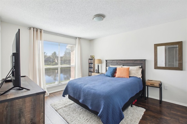 bedroom featuring a textured ceiling, baseboards, and dark wood-style flooring