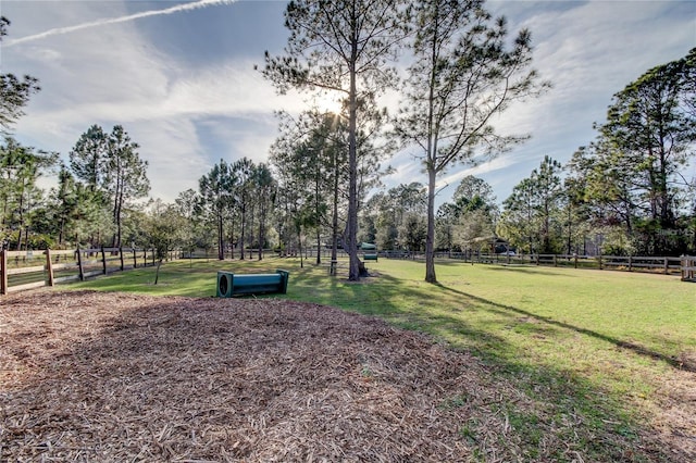 surrounding community featuring a rural view, fence, and a lawn