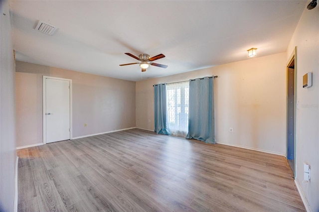 empty room featuring a ceiling fan, baseboards, visible vents, and wood finished floors