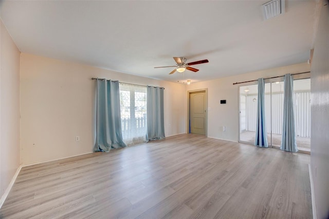 empty room with baseboards, light wood-style flooring, visible vents, and a ceiling fan