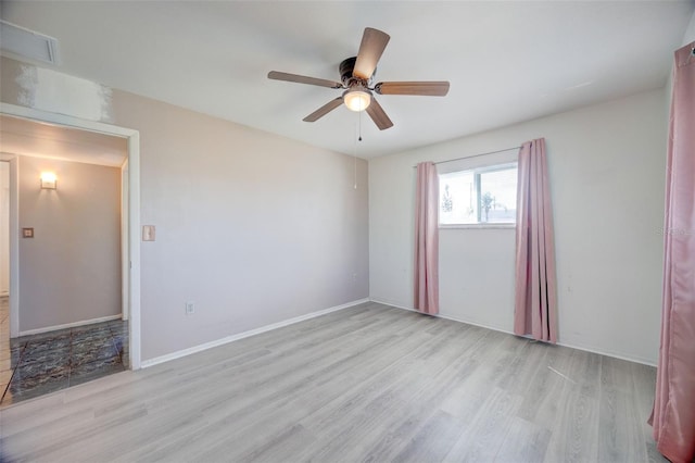 unfurnished room with baseboards, wood finished floors, visible vents, and a ceiling fan