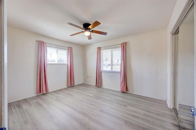 spare room featuring light wood-type flooring, plenty of natural light, and ceiling fan