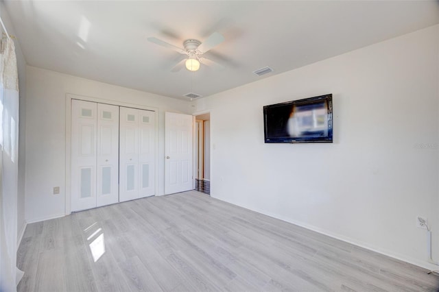 unfurnished bedroom featuring a ceiling fan, a closet, visible vents, and wood finished floors