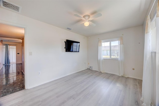 unfurnished room with baseboards, a ceiling fan, visible vents, and light wood-style floors