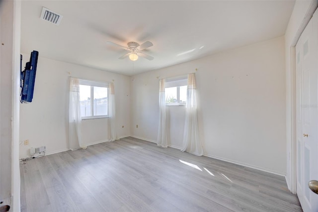 empty room with a wealth of natural light, ceiling fan, and light wood-style flooring